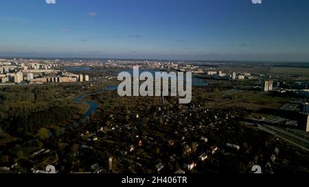 Parco autunnale della città con un fiume. Volare nei sobborghi. All'orizzonte si trovano alti edifici. Fotografia aerea. Foto Stock