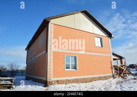 Una semplice casa in mattoni con un tetto a capanna in costruzione in inverno. Foto Stock