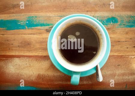 vista dalla parte superiore piatta di una tazza di caffè nero su un tavolo e un piattino verniciati in stile sgranato Foto Stock