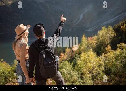 Giovane coppia che viaggia in montagna. Un uomo sta puntando sulla montagna con sfondo naturale Foto Stock