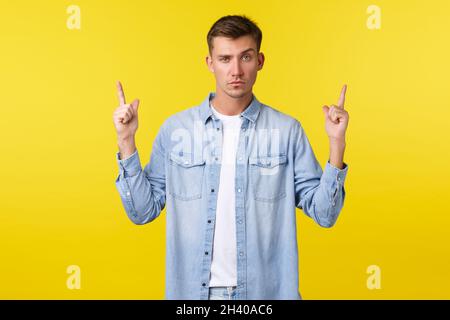 Scettico e dubbioso uomo bello caucasico che ha incredulità in promo banner, puntando le dita in su, sollevare sopracciglia sospettoso, h Foto Stock