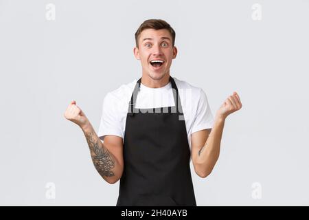 Dipendenti, negozi di alimentari e caffè concetto. Buon e sollievo sorridente barista bello, cameriere in grembiule nero, pompa pugnale Foto Stock