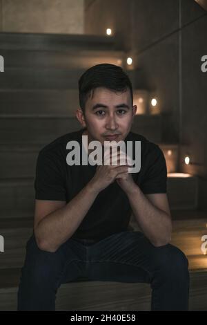 Giovane asiatico bel uomo seduto sul negozio scale. Ragazzo cinese, vita millennial, stile di vita nella grande città, Asia moderna, pausa caffè Foto Stock