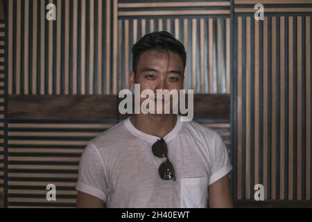 Ritratto di giovane asiatico bello uomo in denim camicia in piedi e sorridente. Gente cinese, vita reale, guardando la macchina fotografica con spazio di copia Foto Stock