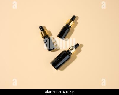 Bottiglie in vetro cosmetico marrone con pipetta su sfondo beige. Cosmetici SPA mockup marchio, vista dall'alto Foto Stock