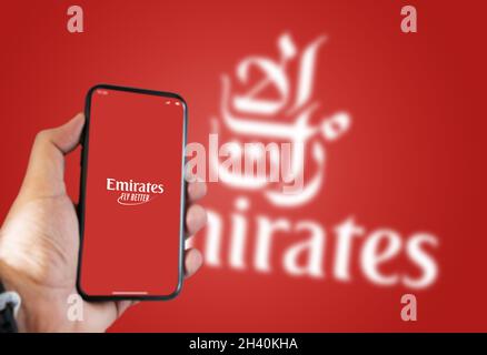 Dubai, Emirati Arabi Uniti, luglio 2021: Una mano che tiene un telefono con l'app Emirates Airline sullo schermo e il logo Emirates sfocato su uno sfondo verde. Foto Stock