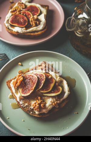 Primo piano di toast alla francese con panna montata e fichi affettati, noci e sciroppo d'acero sul tavolo da cucina grigio. Colazione dolce a casa. Vista dall'alto. Foto Stock