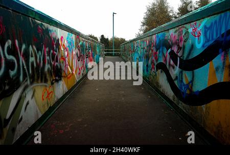 Graffiti colorati sul ponte pedonale della ferrovia che mostra la prospettiva al centro dello schermo Foto Stock