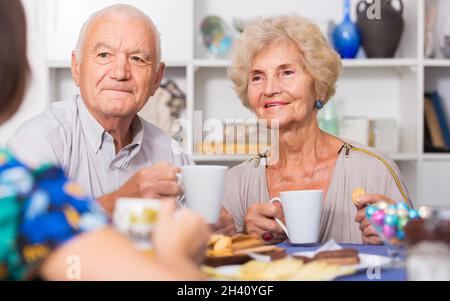 Felice coppia matura bevendo tè con ospite femminile Foto Stock