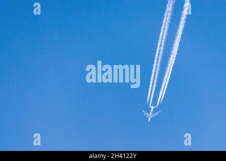Contraglie formate dallo scarico del motore dell'aeroplano contro il cielo blu chiaro. Contraglie o percorsi di vapore sono nubi a forma di linea a volte prodotte da aircr Foto Stock