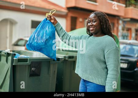 Giovane donna africana che getta fuori la spazzatura alla città Foto Stock