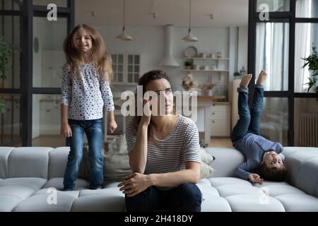 Madre giovane infelice che si sente esausta di bambini piccoli rumorosi. Foto Stock