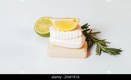 Saponi organici naturali impilano con limone, rosmarino e lime su sfondo bianco, primo piano Foto Stock