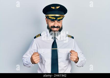 Giovane uomo ispanico che indossa uniforme pilota di aeroplano eccitato per il successo con le braccia sollevate e gli occhi chiusi celebrando la vittoria sorridente. Concetto vincitore. Foto Stock