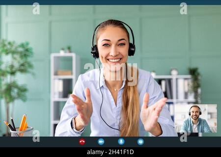 Comunicazione remota a distanza. Giovane donna in cuffia che ha una videochiamata con il suo collega, parlando alla Webcamera Foto Stock