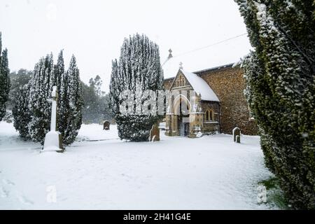 Chiesa di tutti i Santi nel piccolo villaggio di Sutton nella campagna britannica, è completamente coperto di neve profonda durante una rara tempesta di neve nel Regno Unito Foto Stock