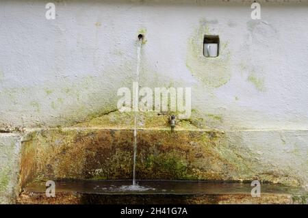 Acqua di sorgente con un canale e una piccola nicchia per una tazza da bere nella catena montuosa del Rhodope in Grecia a nord di Xanthi nell'Europa sudorientale Foto Stock