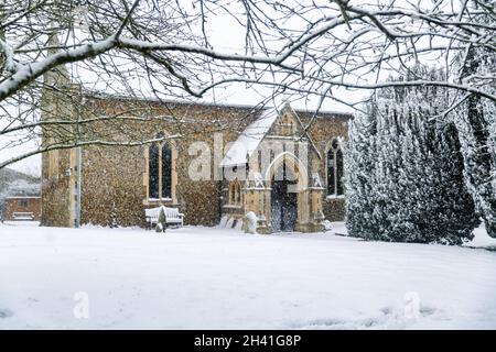 Chiesa di tutti i Santi nel piccolo villaggio di Sutton nella campagna britannica, è completamente coperto di neve profonda durante una rara tempesta di neve nel Regno Unito Foto Stock