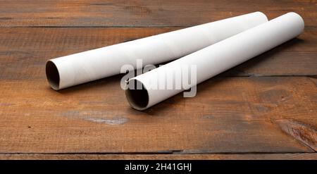 Tubo di carta bianca da un rotolo di asciugamani da cucina, oggetto su uno sfondo di legno marrone Foto Stock