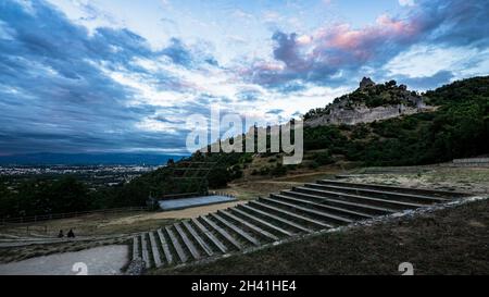 Splendida vista panoramica della città di Valence al tramonto dal punto panoramico di Crussol con anfiteatro in primo piano e collina che domina il castello sul retro Foto Stock