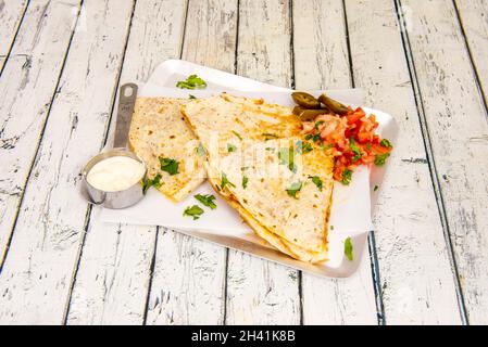 Quesadilla messicana sincronizzata di formaggio fuso con Pico de gallo, jalapeños e formaggio cremoso con prezzemolo e coriandolo Foto Stock