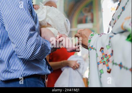 sacramento del battesimo il sacerdote battezza il bambino con l'unzione Foto Stock