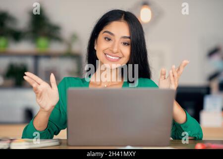 Felice donna medio-orientale che ha una chat video con i colleghi Foto Stock