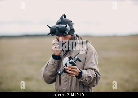 Uomo che controlla il drone quadricottero fpv con occhiali di protezione telecomando antenna Foto Stock