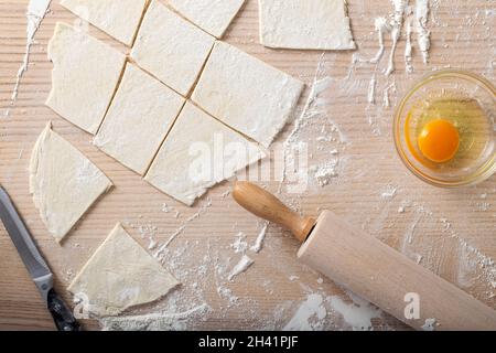 Cottura di ingredienti tra cui uova fresche, farina e un mattarello su tavola di legno - vista dall'alto Foto Stock