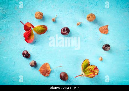 Sfondo autunnale con foglie e castagne vibranti a forma di cuore Foto Stock