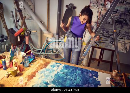 Donna sorridente che si ispira a un camvas in studio d'arte. Foto Stock