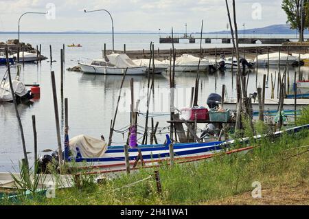 Piccole imbarcazioni a motore ormeggiate su pali di legno del molo di un piccolo porto sul Lago Trasimeno (Umbria, Italia, Europa) Foto Stock