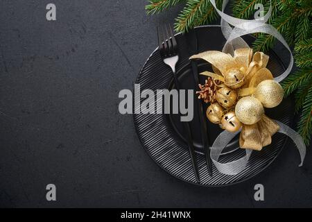 Servito tavolo di natale impostazione vuoto nero piastra di ceramica su sfondo scuro decorazione di Natale. Decorazioni per le vacanze con baubles d'oro e ramo di abete Foto Stock