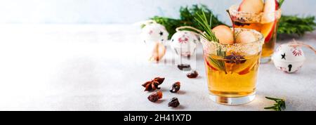 Tradizionale punch di mele natalizie con cannella, anice e rametti di rosmarino su sfondo chiaro. Messa a fuoco selettiva. Vista dall'alto. Foto Stock