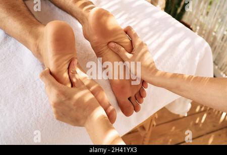 Massaggio ai piedi con olio da massaggio per i piedi maschili mentre ci si rilassa e si riposa presso la spa. Massaggio gambe per uomo Foto Stock