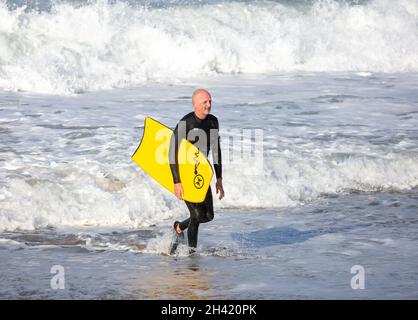 Portreath, Cornovaglia, UK, 31 ottobre 2021.A surfista esce dal mare dopo aver navigato a Portreath, Cornovaglia. Il cielo era blu con sole glorioso e 13C, la previsione è per il tempo umido per i prossimi giorni. Credit: Keith Larby/Alamy Live News Foto Stock