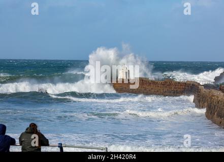 Portreath, Cornovaglia, Regno Unito. 31 ottobre 2021. Gli escursionisti di cani erano fuori per una passeggiata mattutina sulla spiaggia in alta marea a Portreath, Cornovaglia, mentre i surfisti hanno fatto la maggior parte del mare ruvido e grandi onde che si infrangono lungo la parete del porto. Il cielo era blu con sole glorioso e 13C, la previsione è per il tempo umido per i prossimi giorni. Credit: Keith Larby/Alamy Live News Foto Stock