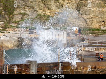 Portreath, Cornovaglia, Regno Unito. 31 ottobre 2021. Gli escursionisti di cani erano fuori per una passeggiata mattutina sulla spiaggia in alta marea a Portreath, Cornovaglia, mentre i surfisti hanno fatto la maggior parte del mare ruvido e grandi onde che si infrangono lungo la parete del porto. Il cielo era blu con sole glorioso e 13C, la previsione è per il tempo umido per i prossimi giorni. Credit: Keith Larby/Alamy Live News Foto Stock