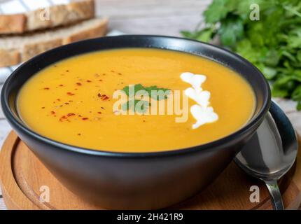 Zuppa di purea di zucca, guarnita con prezzemolo e pepe rosso. Vista laterale Foto Stock