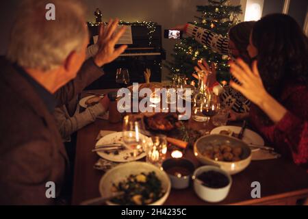 Uomo che prende selfie con la famiglia in cena della vigilia di natale. Famiglia che prende selfie durante la cena di Natale. Foto Stock