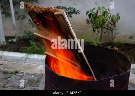 Pezzi di legno bruciati enormi in un barile. Fuoco scintillante Foto Stock