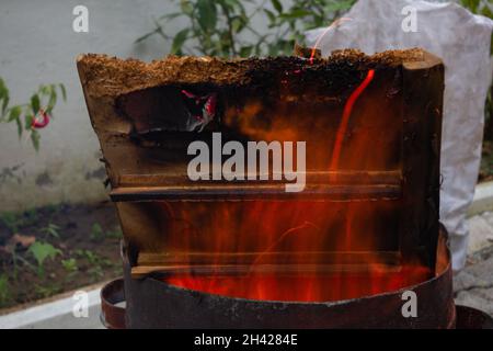 Pezzi di legno bruciati enormi in un barile. Fuoco scintillante Foto Stock