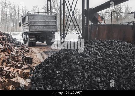 Un autocarro di scarico in una discarica o in un sito industriale ha scaricato una pila di carbone da coke dal cassone. Foto Stock