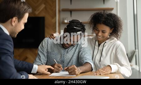 Felice giovani clienti misti gara firma contratto con avvocato. Foto Stock