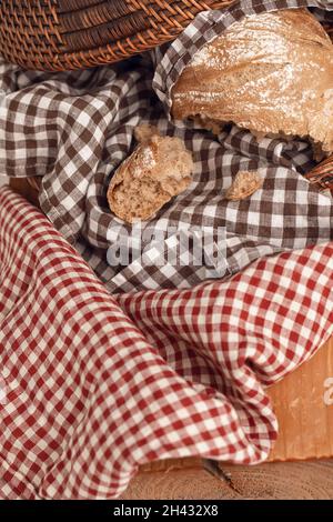 Pagnotta di pane francese fresco fatto in casa in paniere di rattan con biancheria da cucina controllare asciugamani su massello timbro di legno Foto Stock