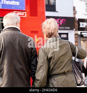 Epsom Surrey London UK, ottobre 31 2021, Senior Man and Woman Holding Hands Waiting to Cross A Busy High Street Road Foto Stock