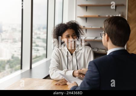 Felice candidato africano americano scuotendo le mani con il datore di lavoro maschile. Foto Stock