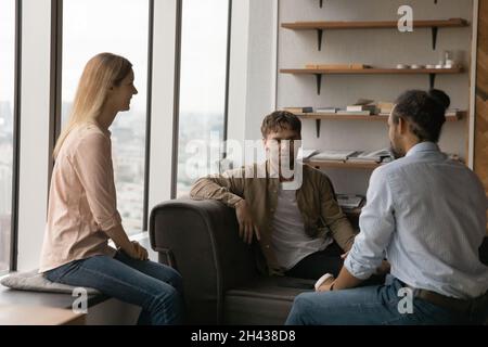 Felice giovani colleghi di gara mista che parlano in ufficio. Foto Stock