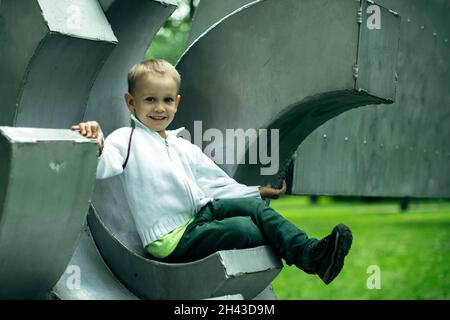 Ritratto di un ragazzo seduto sul parco giochi. Foto Stock