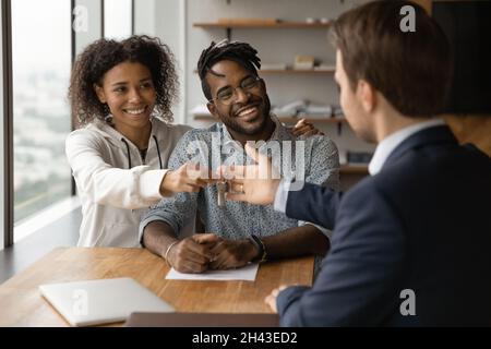 Felice giovane coppia mista di famiglia gara prendendo le chiavi da realtor. Foto Stock